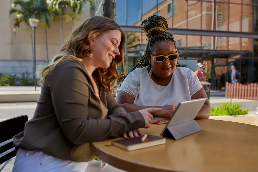 Uma mulher branca e uma mulher negra usando um tablet