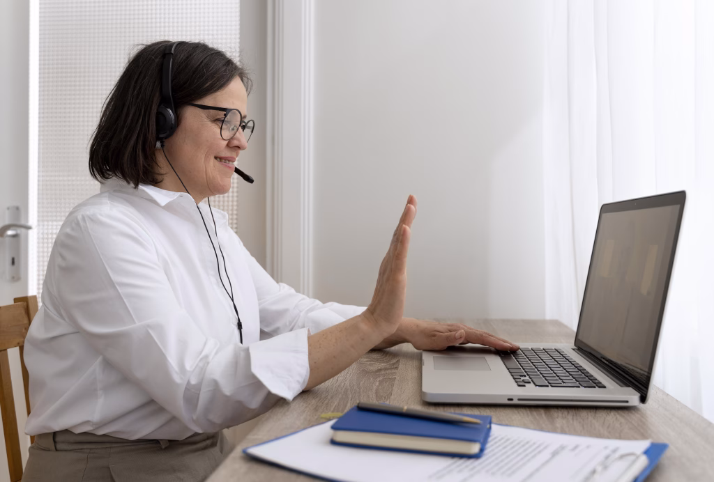 Pessoa está a frente de um laptop e gesticula para a tela, com um fone headset.