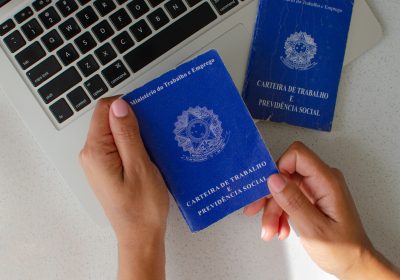 Brazilian Work Card. Translation 'Federative Republic of Brazil, Ministry of Labour'. Concept of FGTS, unemployment, PIS, salary, retirement, employee and Brazilian economy. Hand holding workbook.