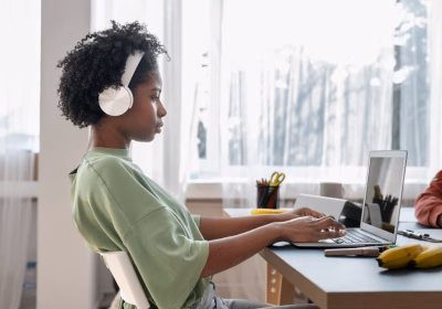 Jovem trabalha na frente do computador, com fones de ouvido. Foto para ilustrar o artigo sobre como conseguir trabalho remoto.