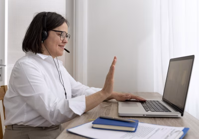 Pessoa está a frente de um laptop e gesticula para a tela, com um fone headset.