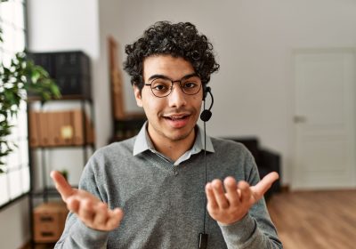 Young hispanic call center agent man smiling happy working at the office.