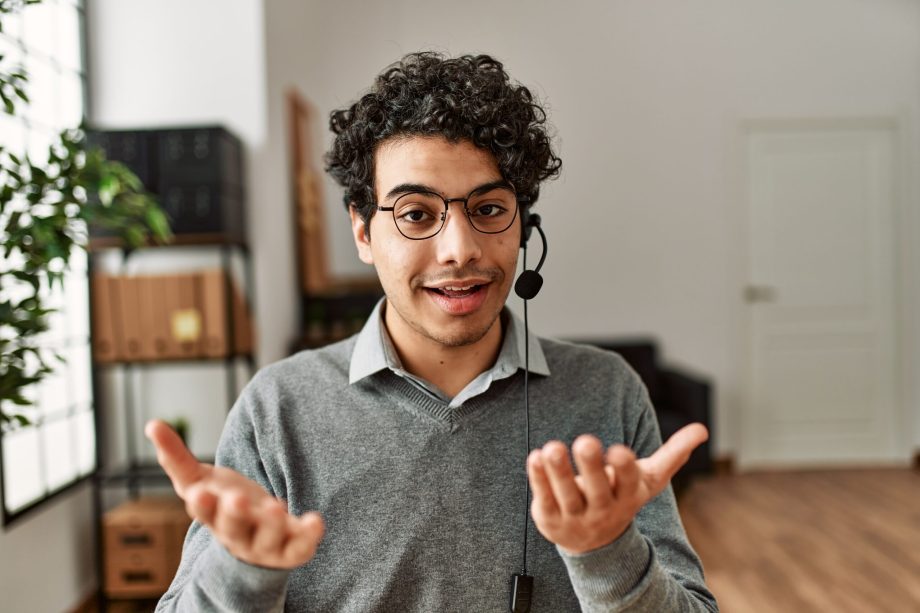 Young hispanic call center agent man smiling happy working at the office.