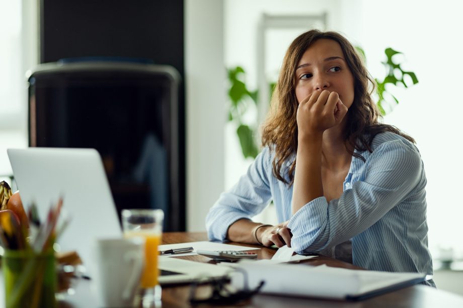 Young worried woman thinking of something while calculating her  home budget.